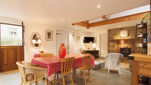 A dining area with a red polka dot tablecloth, wicker chairs, a large vase, and a stone fireplace. - 3 bedroom accommodation in Shadycombe Road (Shadycombe Road)