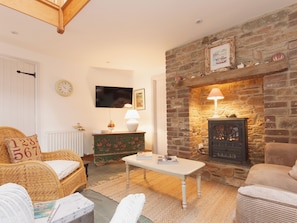 A cozy living room with a stone fireplace, a television, and a comfortable seating area. - 3 bedroom accommodation in Shadycombe Road (Shadycombe Road)