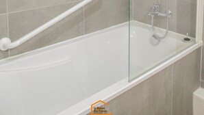 A modern bathroom with a glass-enclosed shower, a white bathtub, and a grab bar. - Apartment du Puits Salé (Lons-le-Saunier)