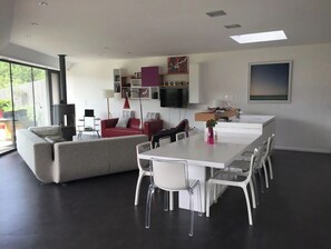 Un salon moderne avec un canapé, une table à manger et des chaises, un téléviseur et une cheminée.