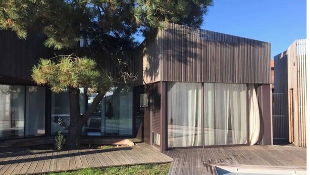 A modern house with a wooden deck, a swimming pool, and a large tree. - Architect-designed villa, walking distance to beach and town center, heated pool (Capbreton)