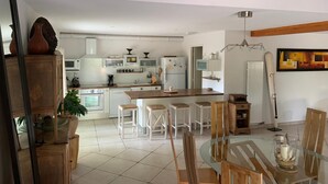 A modern kitchen with white appliances, a dining area with wooden furniture, and a large painting on the wall. - L'ancienne Etable Gîte Dordogne (Saint-Avit-Saint-Nazaire)