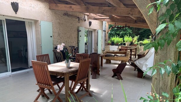 A covered patio with wooden furniture, a dining table, and chairs. - L'ancienne Etable Gîte Dordogne (Saint-Avit-Saint-Nazaire)