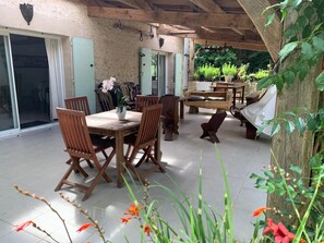 Un porche cubierto con muebles de madera, una mesa de comedor y sillas.