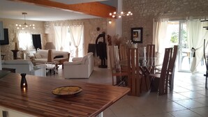 A spacious living area with a wooden dining table, white sofas, and a stone wall. - L'ancienne Etable Gîte Dordogne (Saint-Avit-Saint-Nazaire)