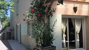 A building with a wooden pergola, a potted plant, and a door with curtains. - L'ancienne Etable Gîte Dordogne (Saint-Avit-Saint-Nazaire)