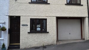 Ein zweistöckiges Gebäude mit einer strukturierten Fassade, einer dunkelbraunen Tür und einer Garagentür.