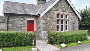 A stone house with a red door, white windows, and a stone chimney. - 2 bedroom accommodation in Bassenthwaite, near Keswick (Bassenthwaite, near Keswick)