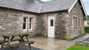 A stone house with a tiled roof, a wooden door, and a picnic table in the foreground. - 2 bedroom accommodation in Bassenthwaite, near Keswick (Bassenthwaite, near Keswick)