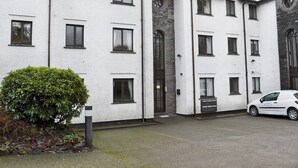 A multi-story building with a white exterior, multiple windows, and a stone facade. - 2 bedroom accommodation in Bowness on Windermere (Bowness on Windermere)