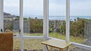 Una habitación con un amplio ventanal con vistas a un litoral rocoso y al mar.