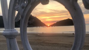 A beach scene with a sunset, a fence, and a distant shoreline. - CONCHA CITY CENTER, FREE PARKING! Top location. Air Conditioning !  (Donostia)