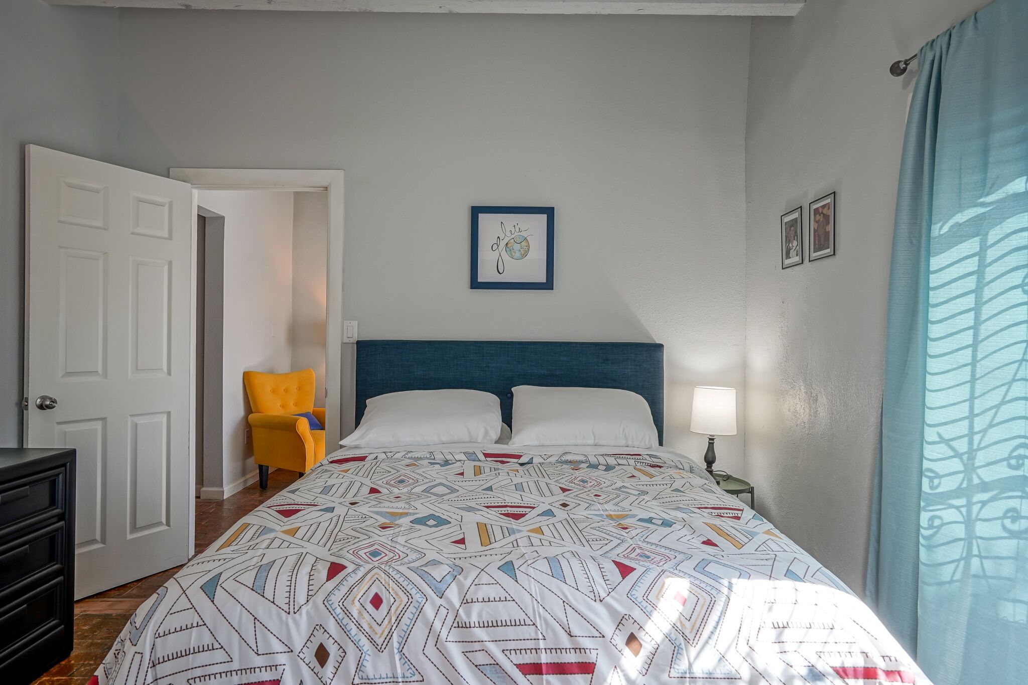 A bedroom with a bed, a nightstand, a chair, and a door.