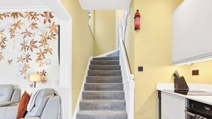 Una escalera conduce a una cocina con un extintor de incendios fijado a la pared.