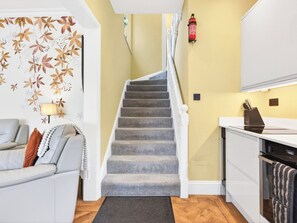 A staircase leading to a kitchen with a fire extinguisher mounted on the wall. - 2 bedroom accommodation in Bowness on Windermere (Bowness on Windermere)
