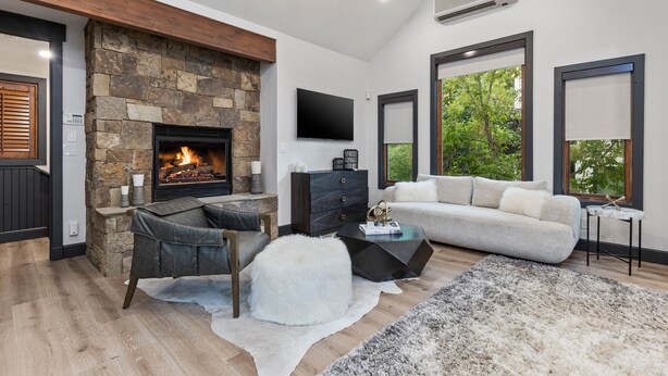 Una sala moderna con chimenea de piedra, televisor de pantalla plana, sofá y mesa de centro.