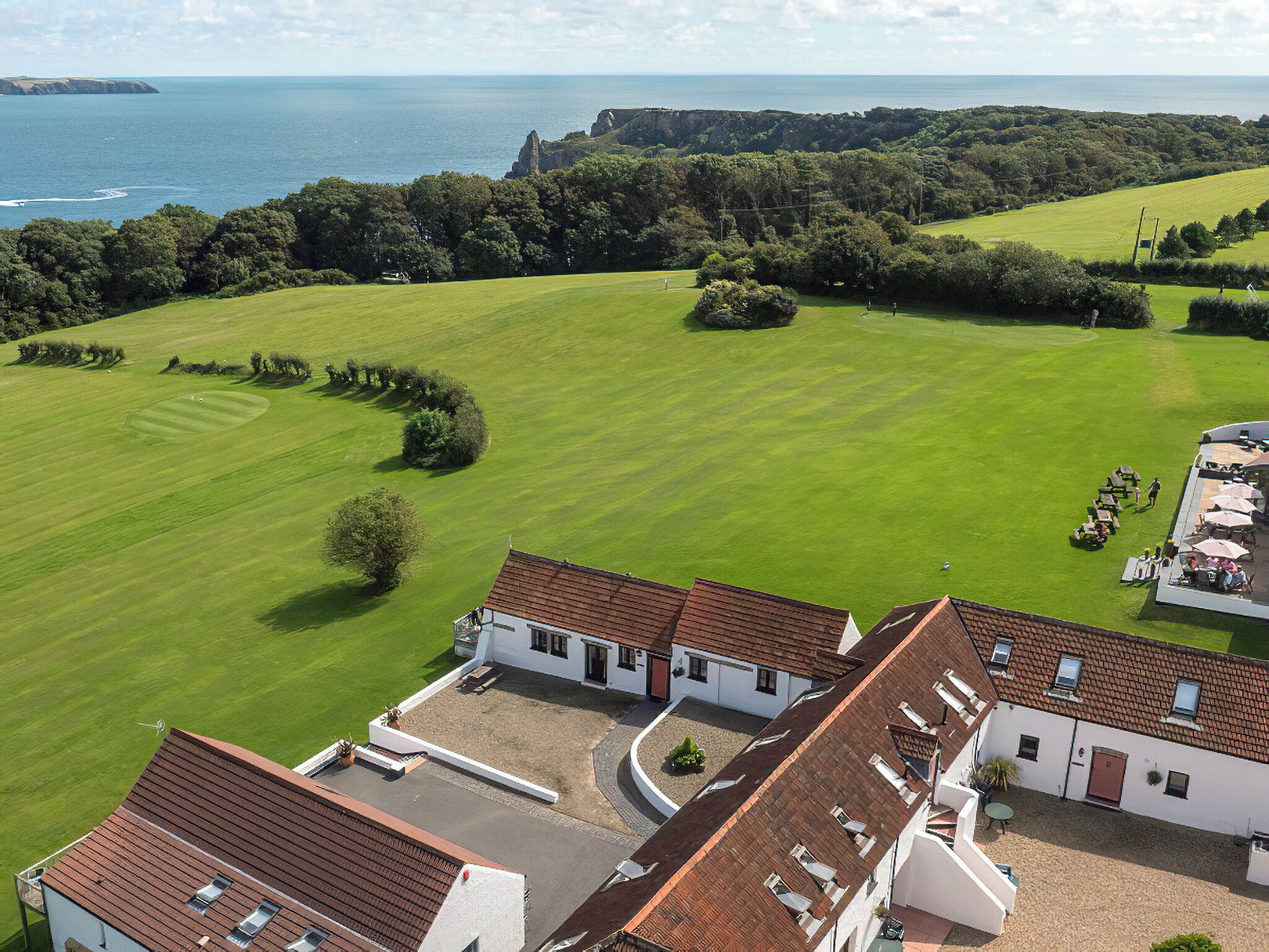A golf course with a clubhouse and a view of the sea.