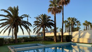 A swimming pool with palm trees and a view of the sea.