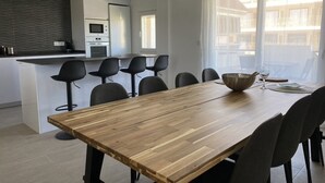 A modern kitchen with a wooden dining table and black chairs.