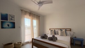 A bedroom with a bed, a ceiling fan, a nightstand, and a window with curtains.