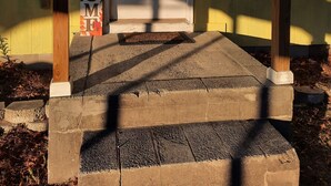Une entrée de maison avec une porte blanche, une pancarte de bienvenue et une structure de porche en bois.