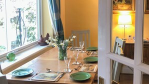 A dining table set with plates, cutlery, and glasses, a vase with flowers, and a window with curtains. - 3 bedroom accommodation in Beadnell (Beadnell)