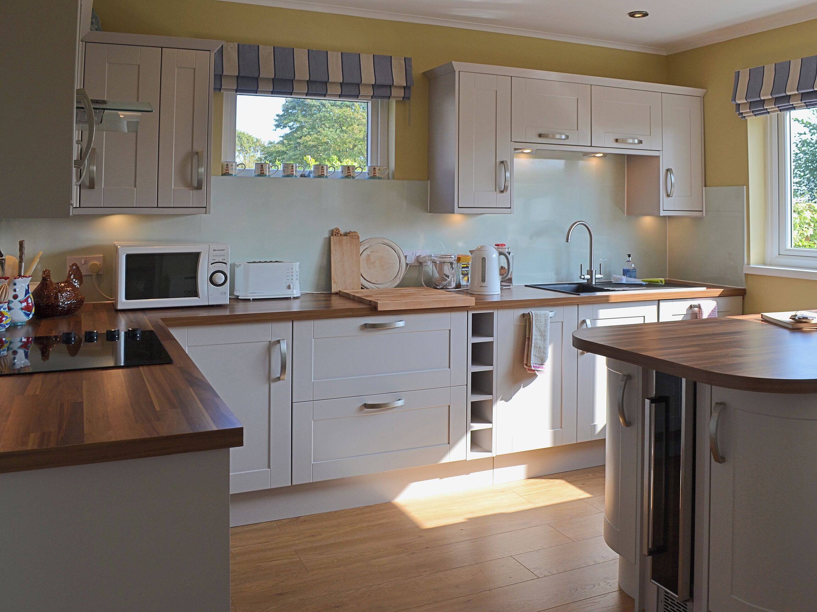 A kitchen with white cabinets, a microwave, a toaster, and a sink.