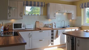 A kitchen with white cabinets, a microwave, a toaster, and a sink. - 3 bedroom accommodation in Beadnell (Beadnell)