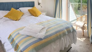 A neatly made bed with a striped blanket, two pillows, and a white towel. - 3 bedroom accommodation in Beadnell (Beadnell)