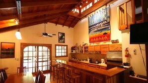 Une cuisine spacieuse avec des meubles en bois, un grand îlot central doté de tabourets et un ventilateur de plafond.