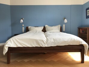 Cozy retreat with a neatly made bed, wooden headboard, and a herringbone floor.