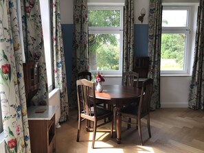 Enjoy meals in this cozy dining area with a round table and four chairs, surrounded by windows and a stylish cabinet.