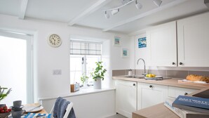 Une cuisine moderne avec des meubles blancs, un évier et une fenêtre donnant sur un beau paysage.