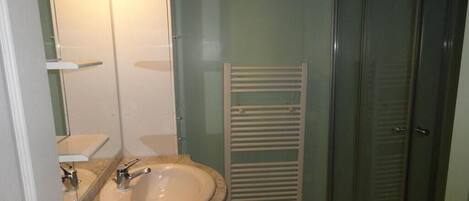 Un baño con lavamanos, espejo y cabina de ducha de vidrio.