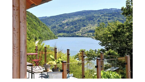 Una terraza de madera con vista a un lago y las colinas circundantes.
