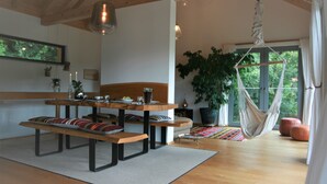 Un amplio salón con una mesa de madera, bancos y una hamaca.
