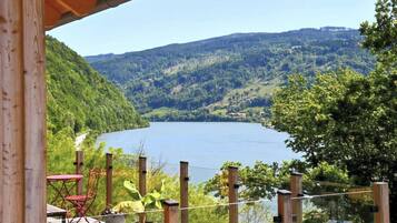 Eine Holzterrasse mit Blick auf einen See und die umliegenden Hügel.