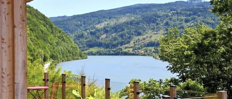 Una terraza de madera con vista a un lago y las colinas circundantes.
