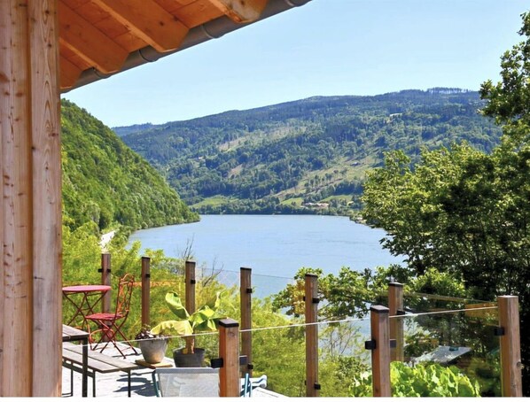 Una terraza de madera con vista a un lago y las colinas circundantes.