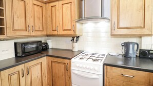 Une cuisine avec des meubles de rangement en bois, un four à micro-ondes, une cuisinière et une machine à café.