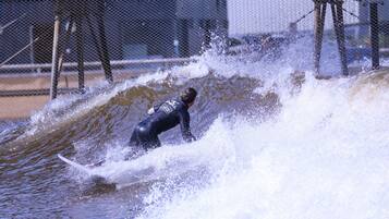 A person surfing on a wave in a fenced area.