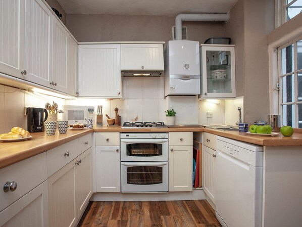 A kitchen with white cabinets, a stove, oven, and a dishwasher.