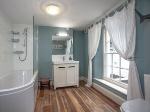 A bathroom with a bathtub, shower, vanity, and a window with curtains. - 4 bedroom accommodation in Cliff Rd/Courtenay (Cliff Rd/Courtenay)