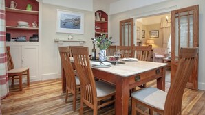 Un coin repas avec une table en bois, des chaises et un tableau accroché au mur.