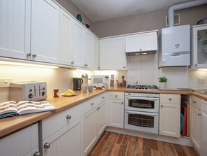 A kitchen with white cabinets, a stove, oven, microwave, and a book on the counter. - 4 bedroom accommodation in Cliff Rd/Courtenay (Cliff Rd/Courtenay)
