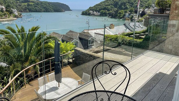 A balcony with a view of a coastal town, a table, and chairs. - 2 bedroom accommodation in Above Town (Above Town)
