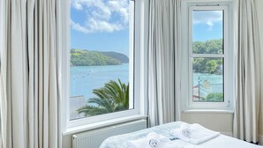 A hotel room with a large window offering a view of a bay with boats and greenery. - 2 bedroom accommodation in Above Town (Above Town)