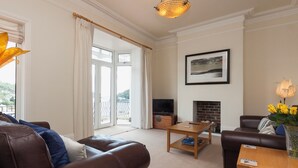 A living room with a brown leather sofa, a wooden coffee table, a television, and a fireplace. - 2 bedroom accommodation in Above Town (Above Town)