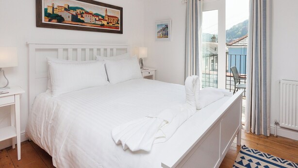 A white bedroom with a bed, nightstands, and a painting on the wall. - 2 bedroom accommodation in 6 Horn Hill Steps (6 Horn Hill Steps)