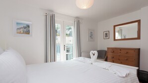 A hotel room with a bed, a dresser, a mirror, and a window with curtains. - 2 bedroom accommodation in 6 Horn Hill Steps (6 Horn Hill Steps)